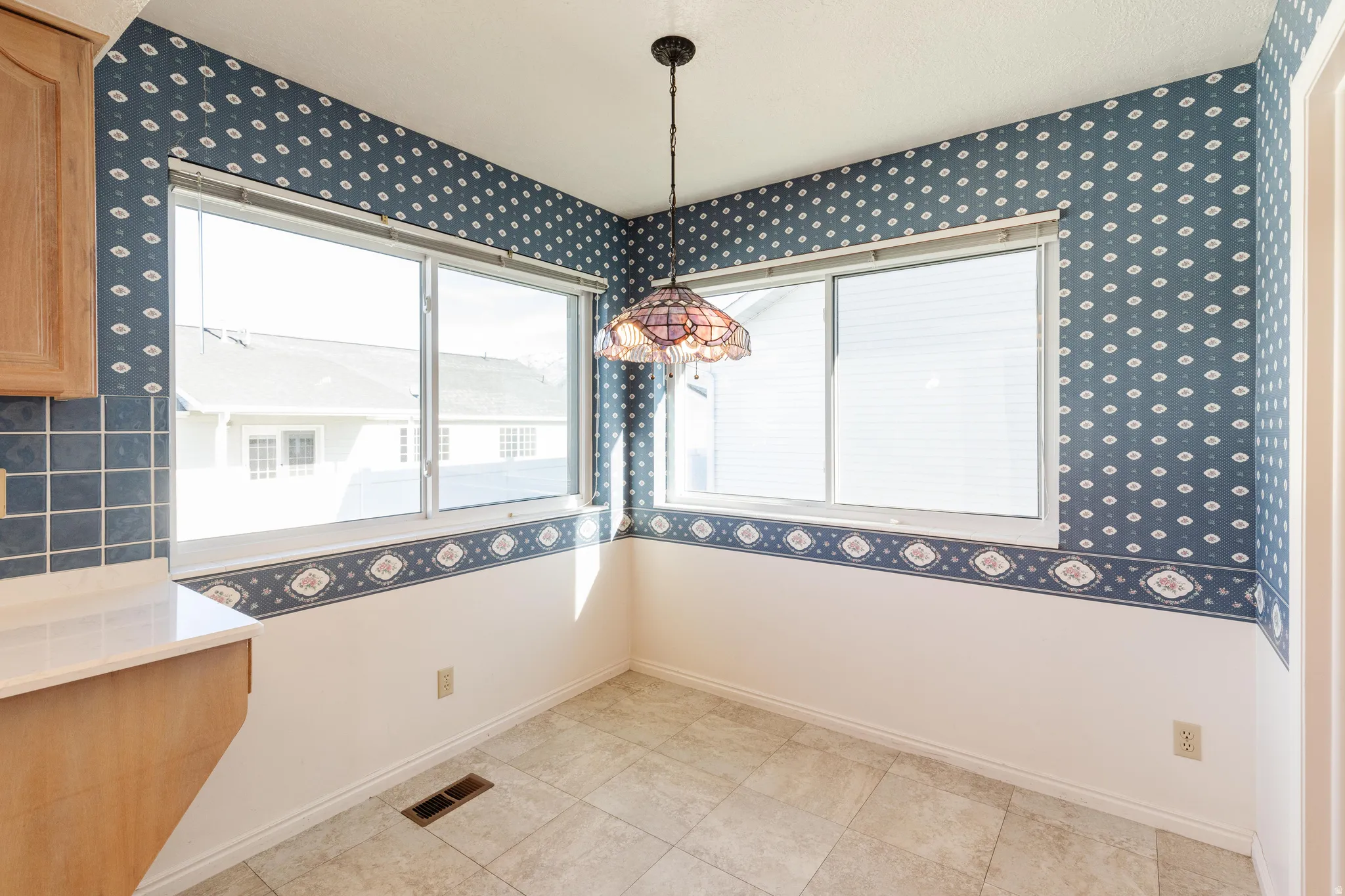 Unfurnished dining area featuring wallpapered walls and light tile patterned flooring