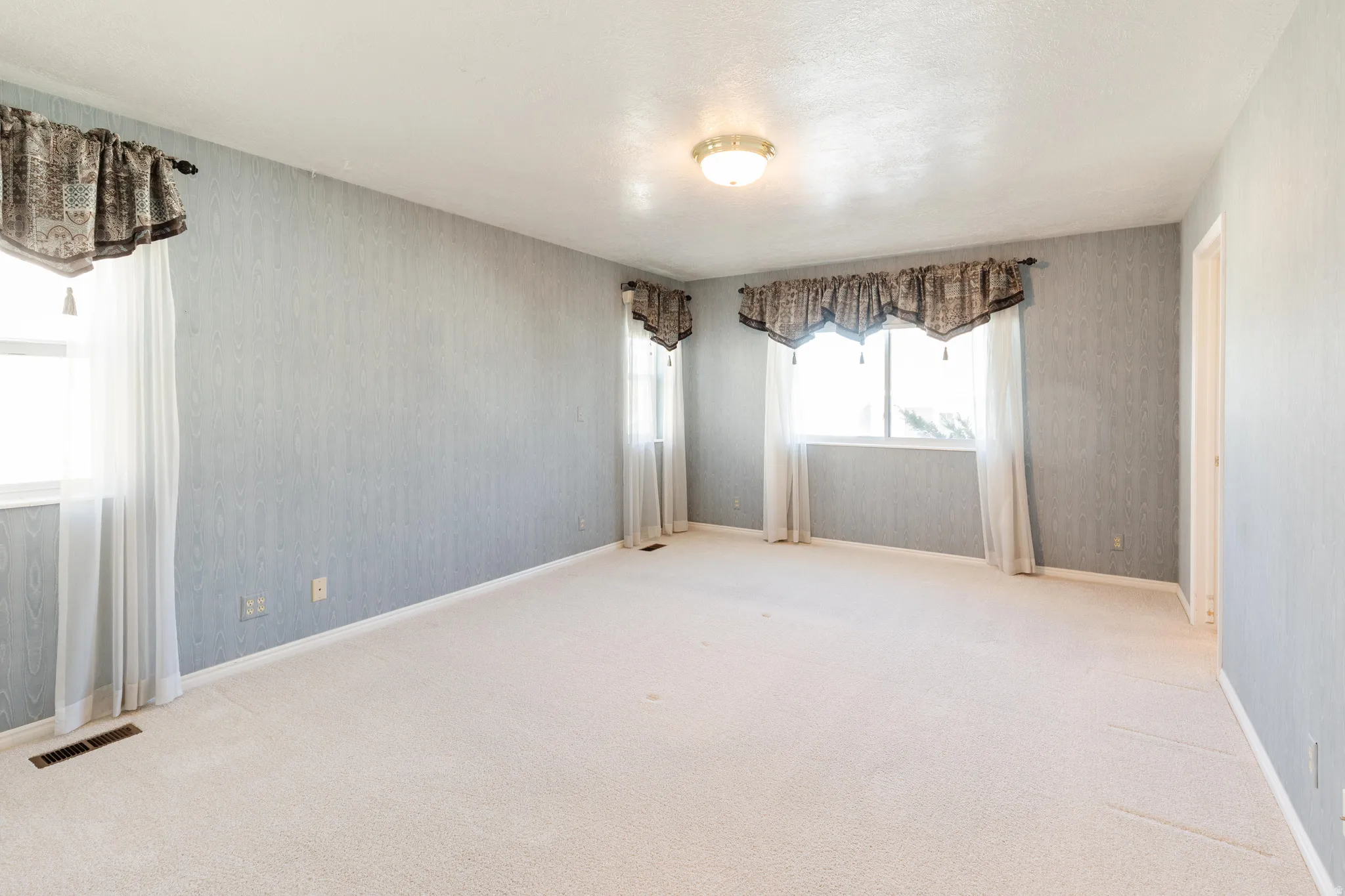 Carpeted empty room with baseboards and wallpapered walls