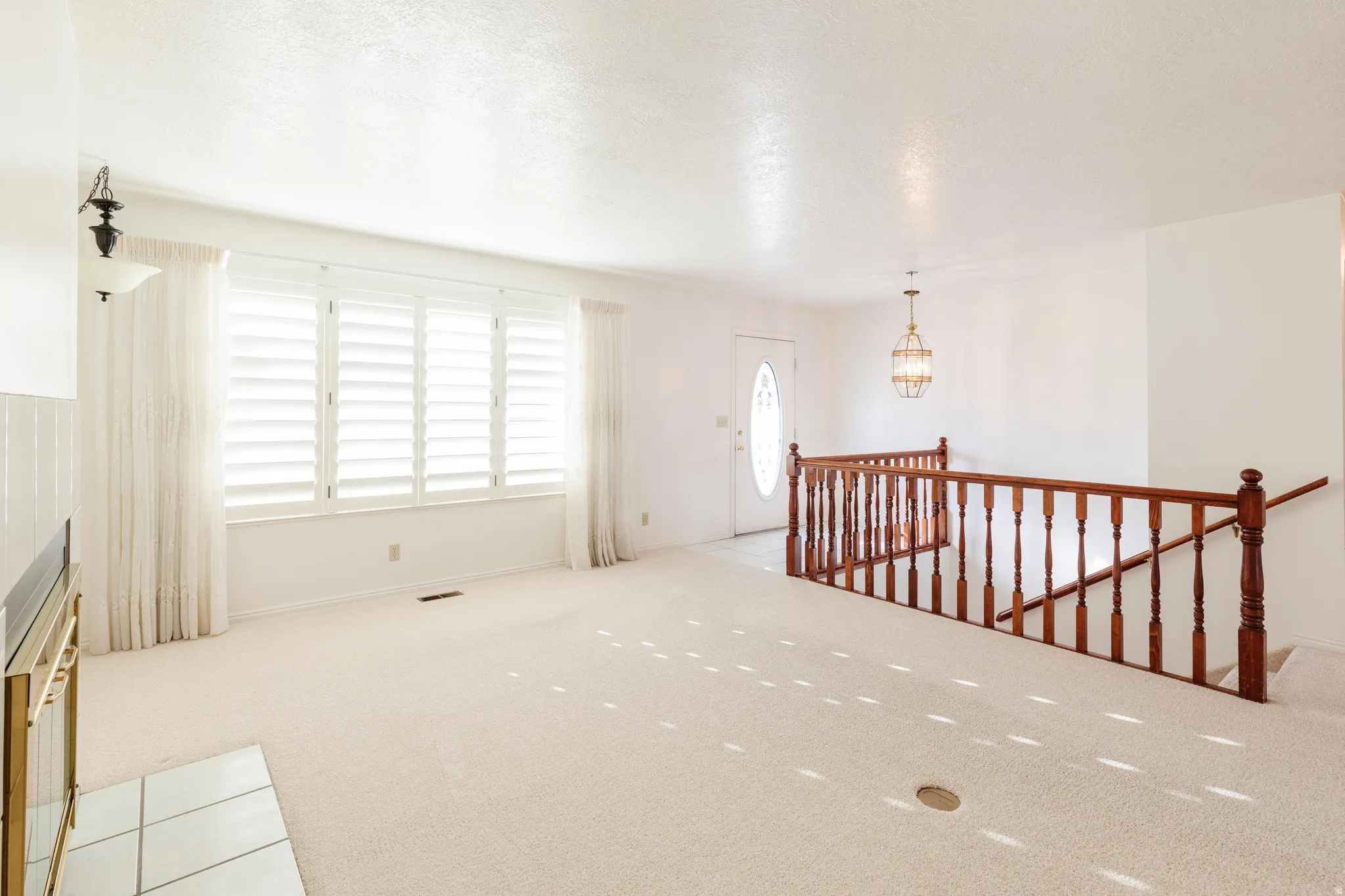Empty room with light carpet and a chandelier