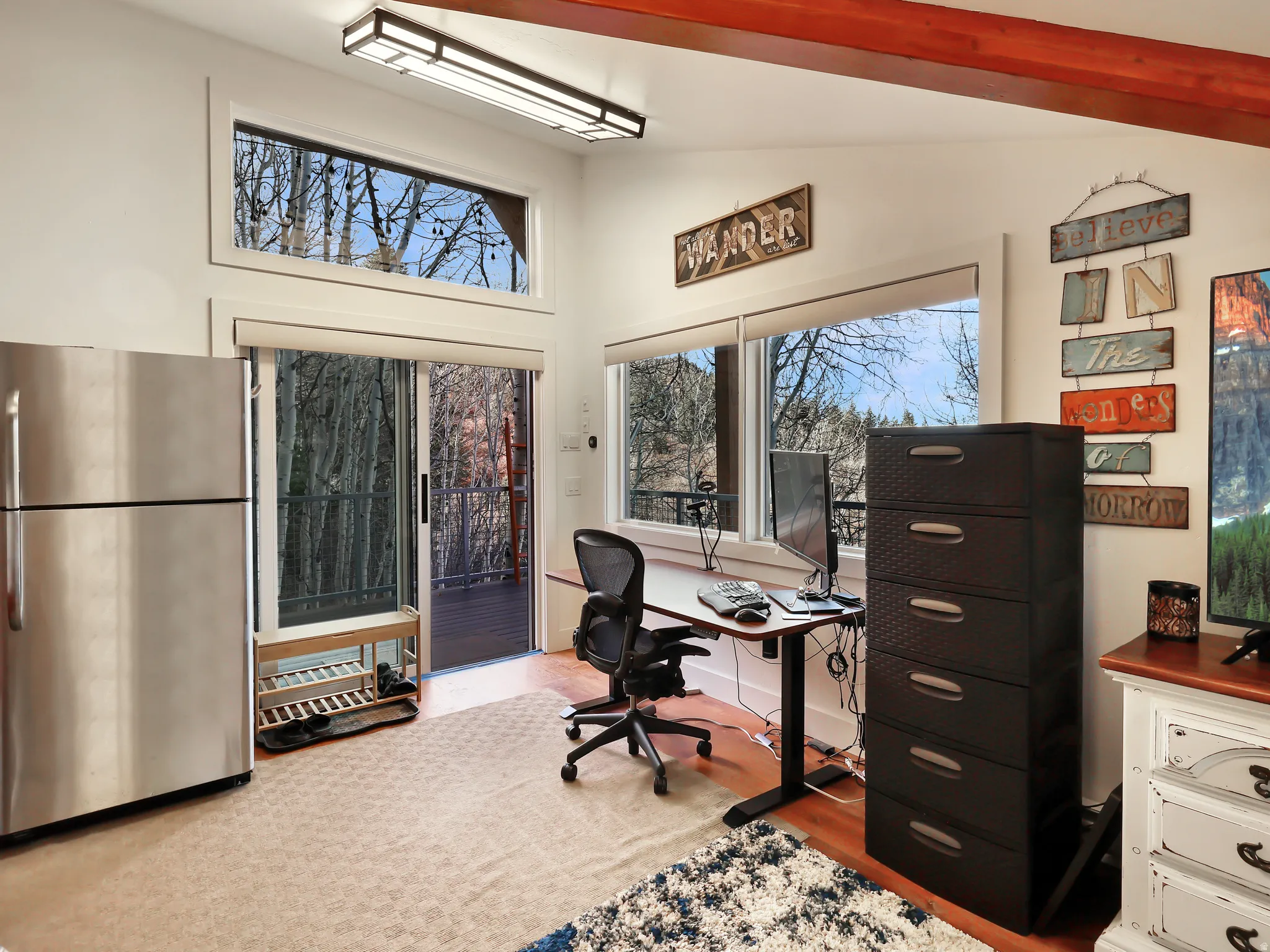 Office space featuring light wood-style flooring and high vaulted ceiling
