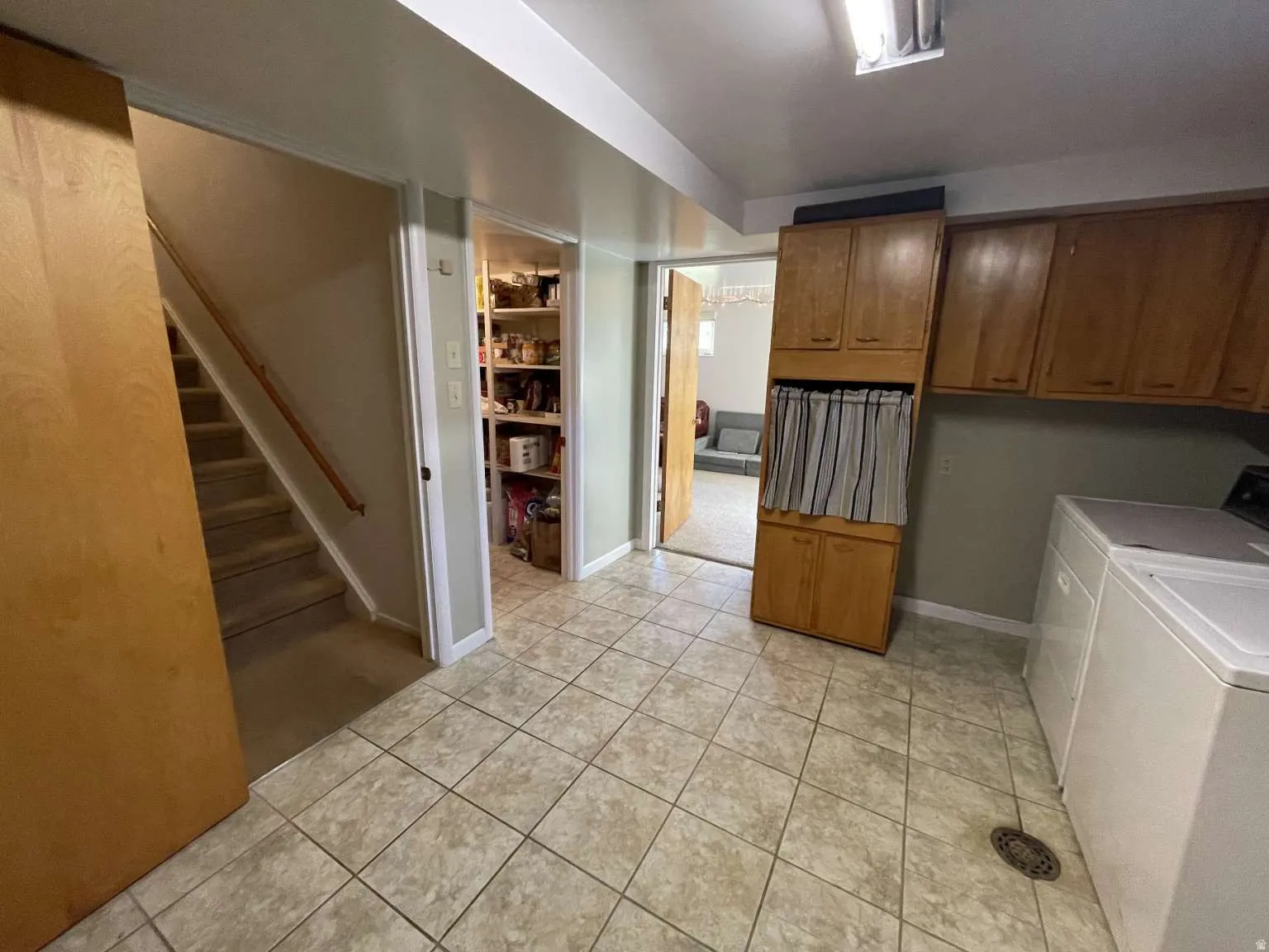 Laundry room with washing machine and dryer, light tile patterned floors, and cabinet space