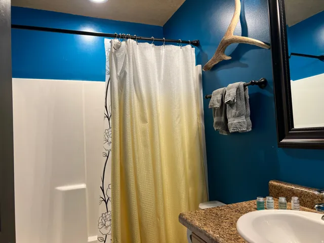 Bathroom featuring vanity and shower / bathtub combination with curtain