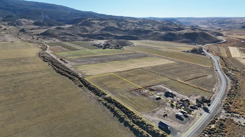 Overview of rural landscape featuring rows of crops, property boundaries highlighted, and a mountainous background