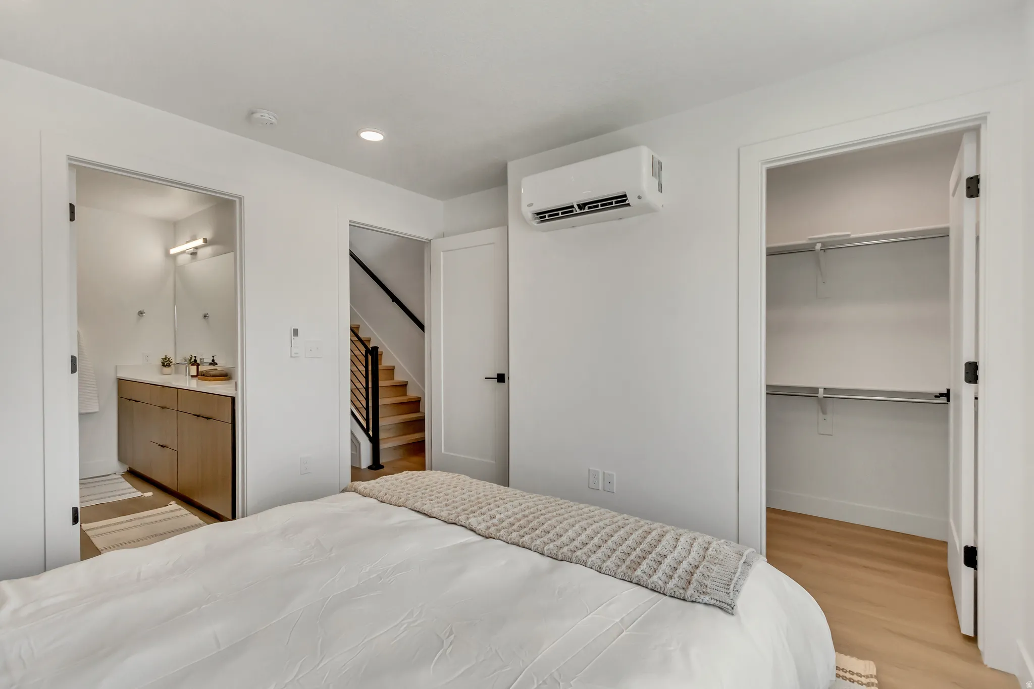 Bedroom with a walk in closet, light wood finished floors, a wall mounted air conditioner, and recessed lighting