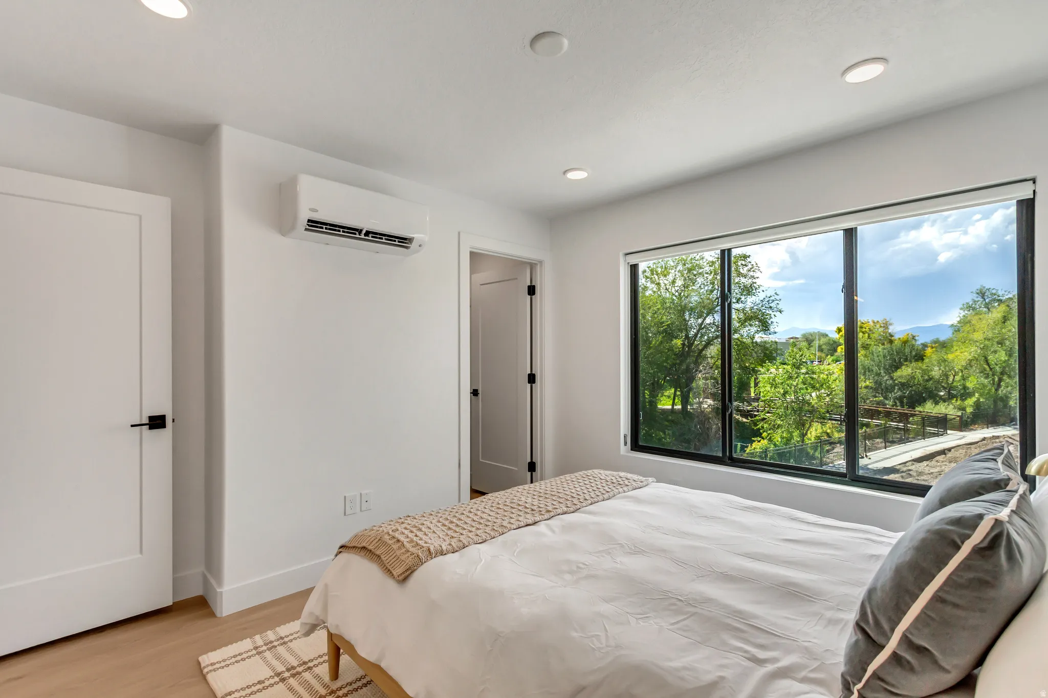 Bedroom featuring an AC wall unit, light wood finished floors, and recessed lighting