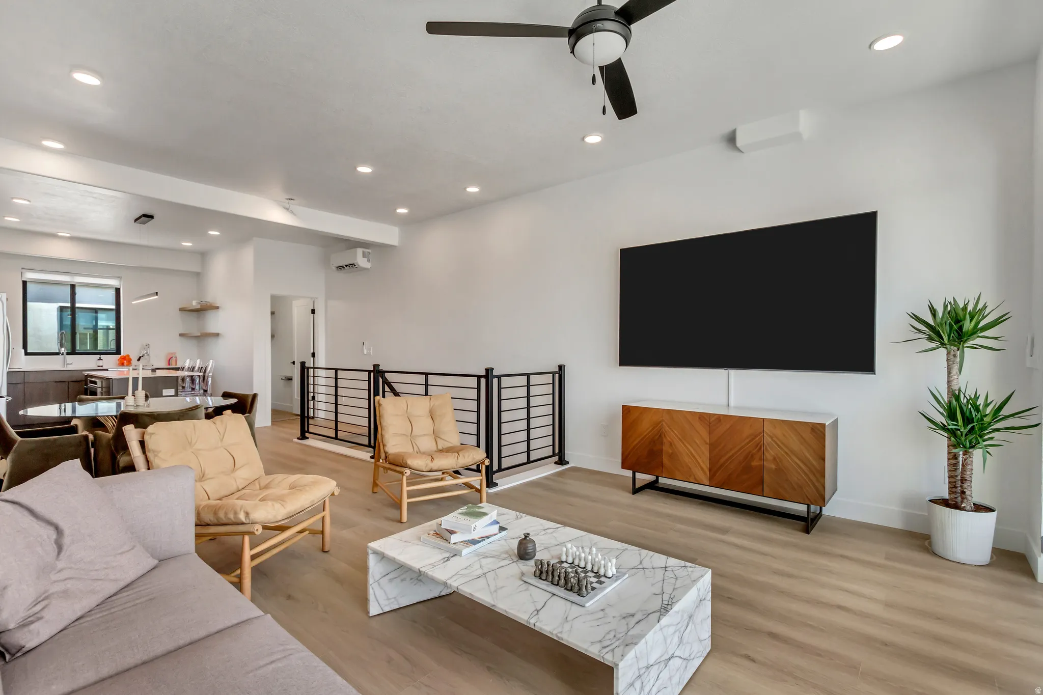 Living room with recessed lighting, light wood finished floors, ceiling fan, and a wall mounted air conditioner