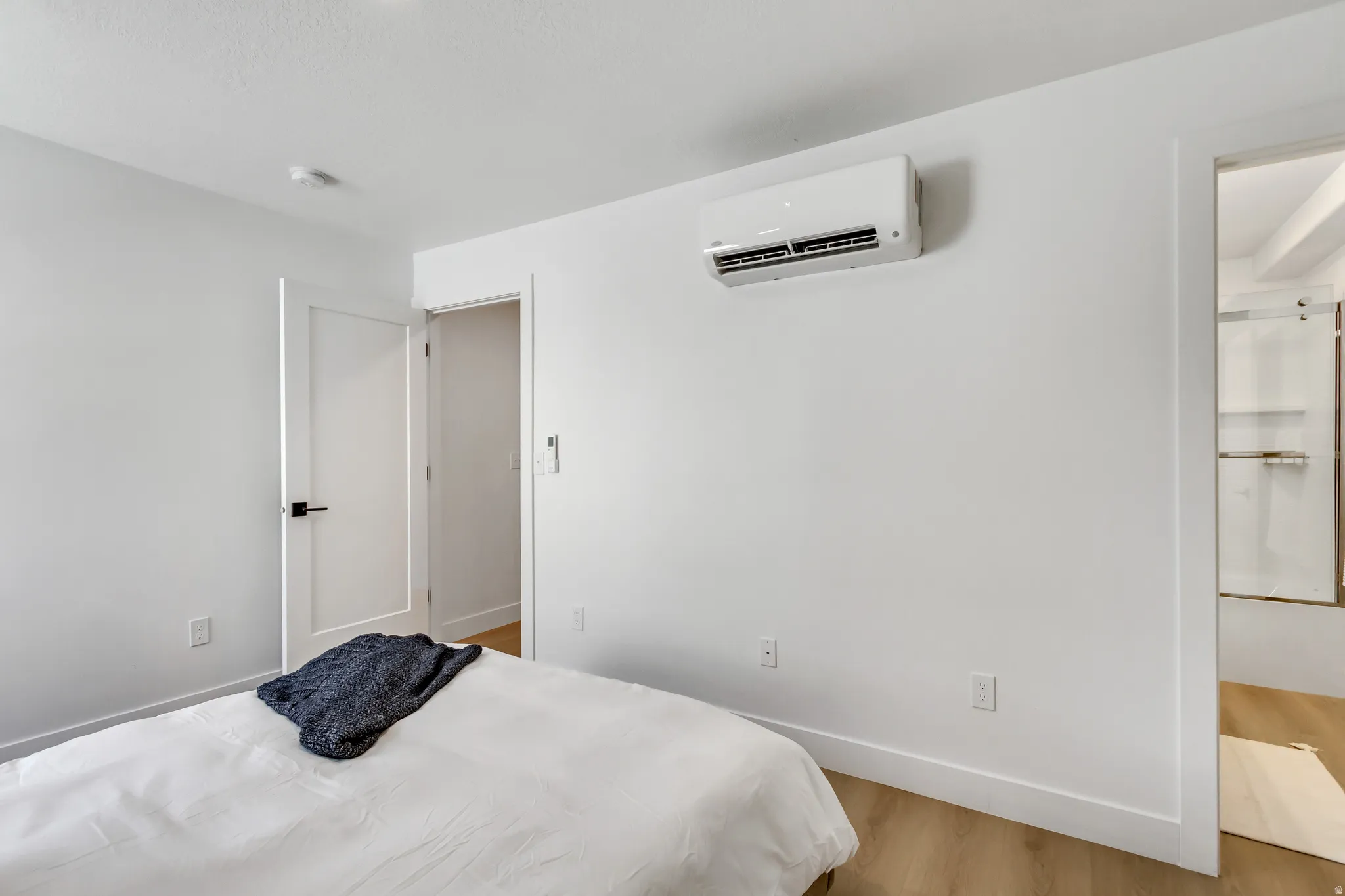 Bedroom featuring light wood-style flooring and a wall mounted AC
