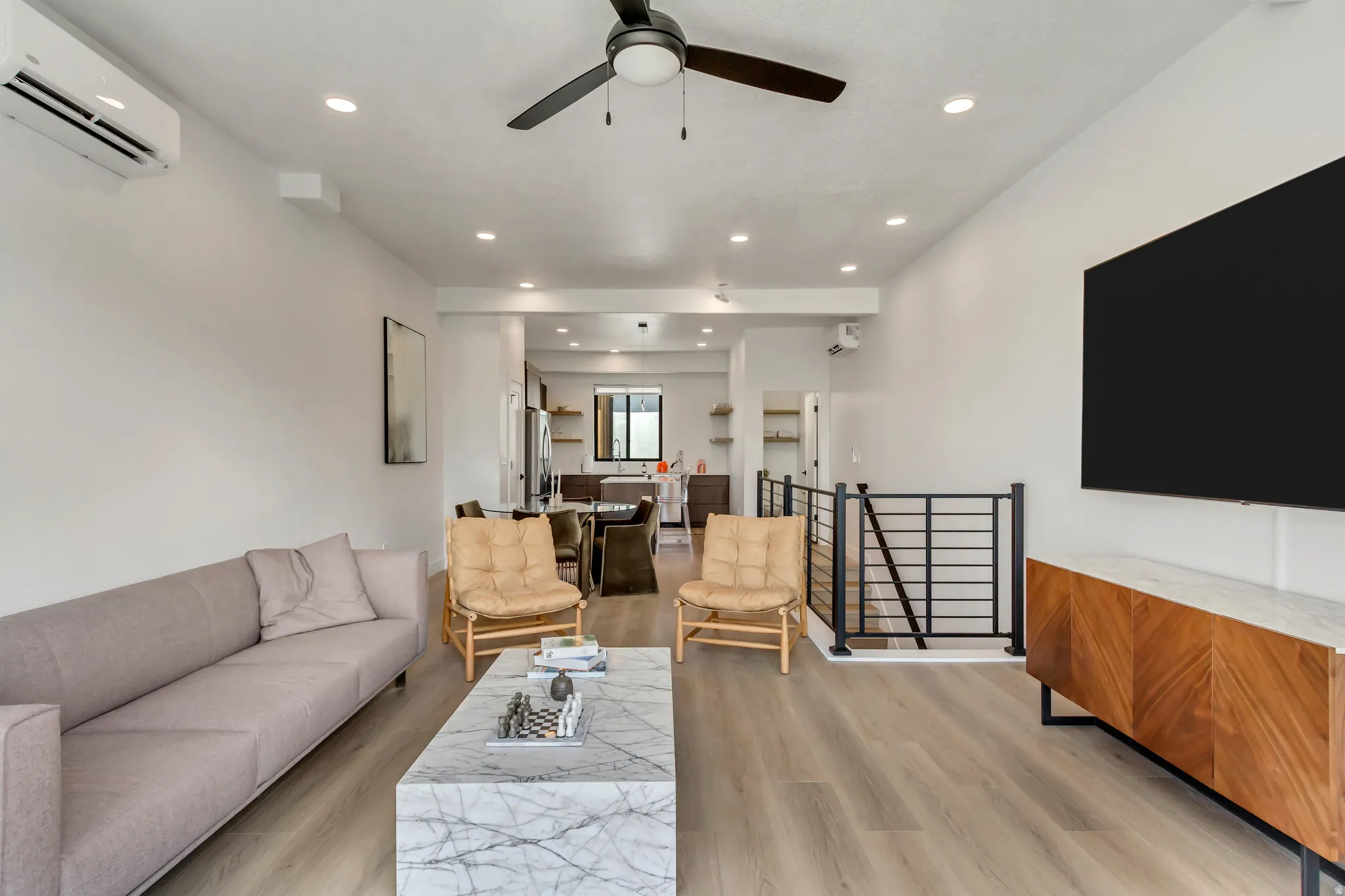 Living area with a wall mounted AC, light wood-style floors, a ceiling fan, and recessed lighting