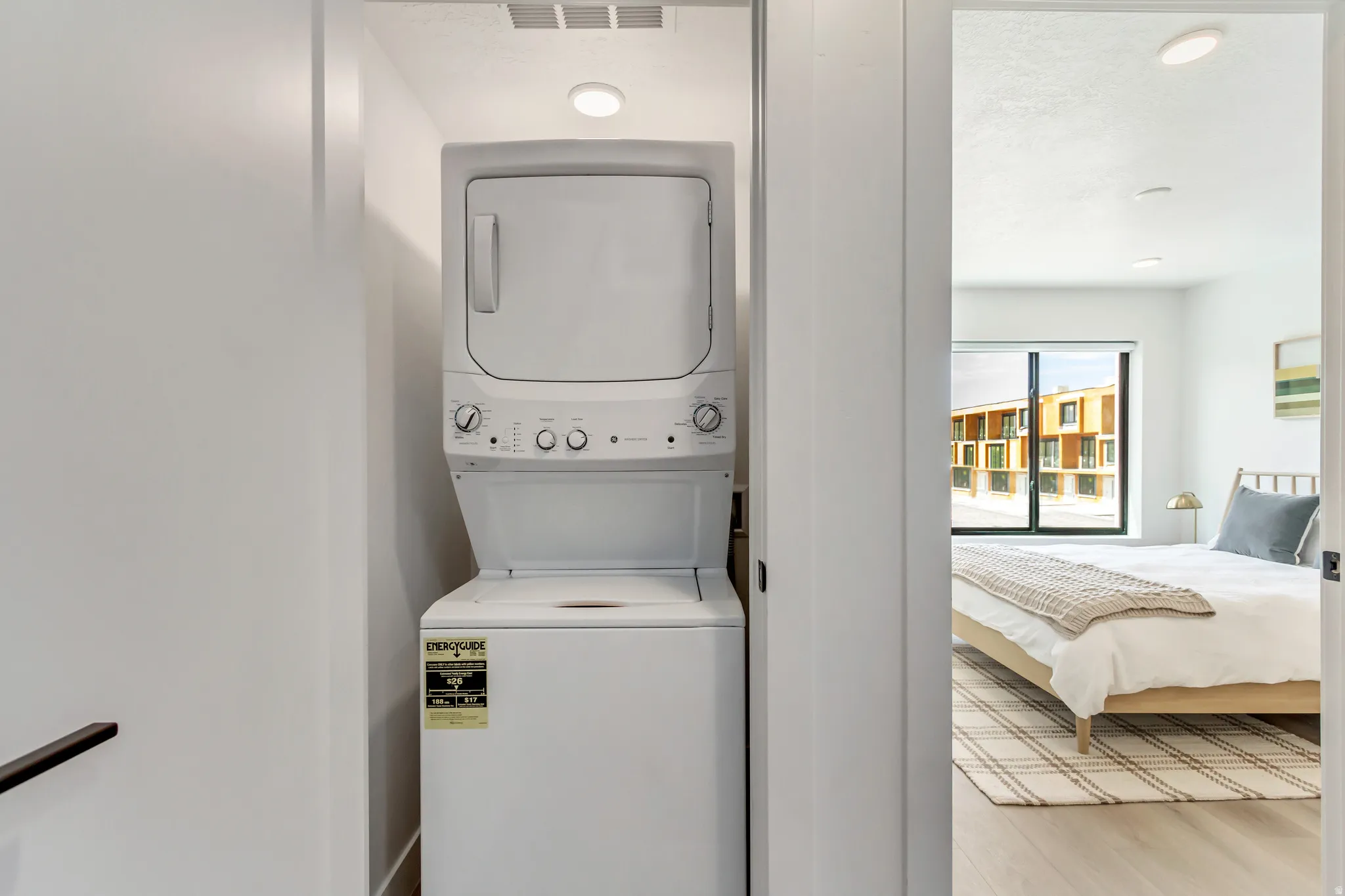 Laundry area featuring stacked washer / drying machine, light wood finished floors, and recessed lighting