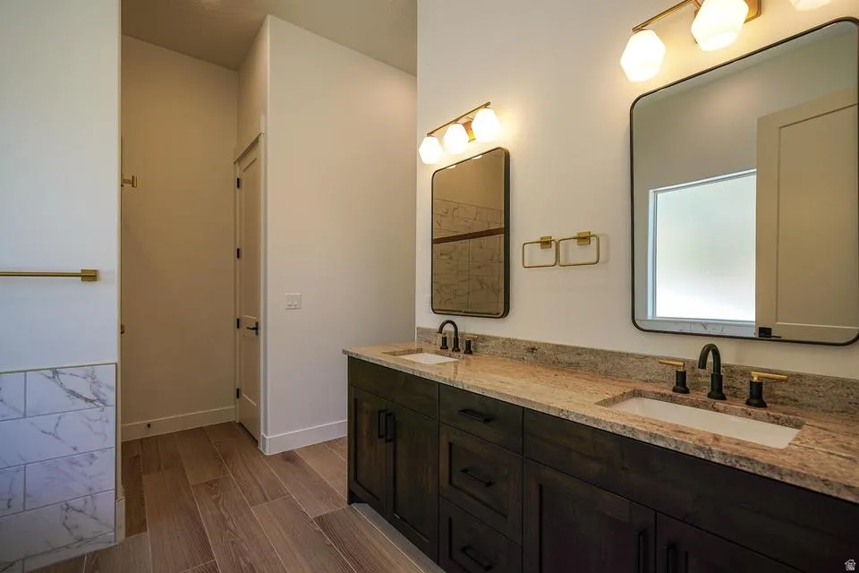 Dual vanity featuring dark wood cabinetry, light-toned granite countertops, and undermount sinks
