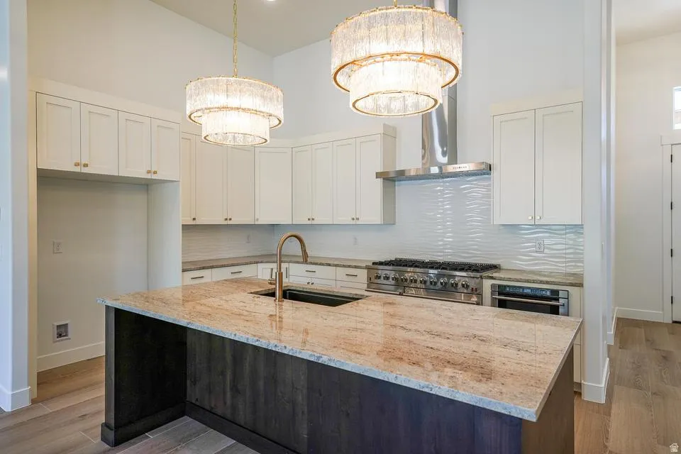 Kitchen featuring a large island with a stone countertop, an undermount sink, and a high-arc faucet
