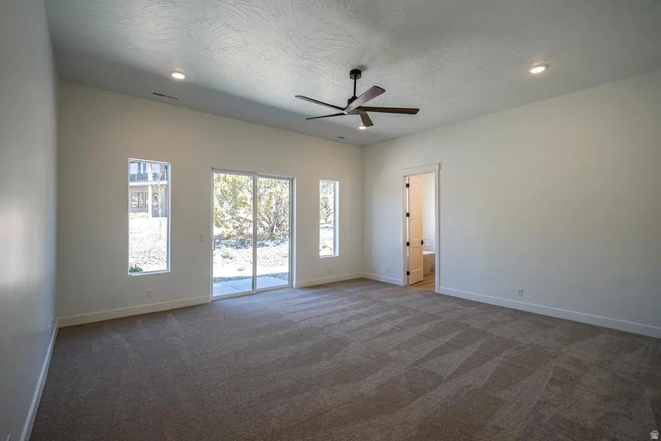 Spacious room featuring carpeting, recessed lighting, ceiling fan, and a glass sliding door to the exterior