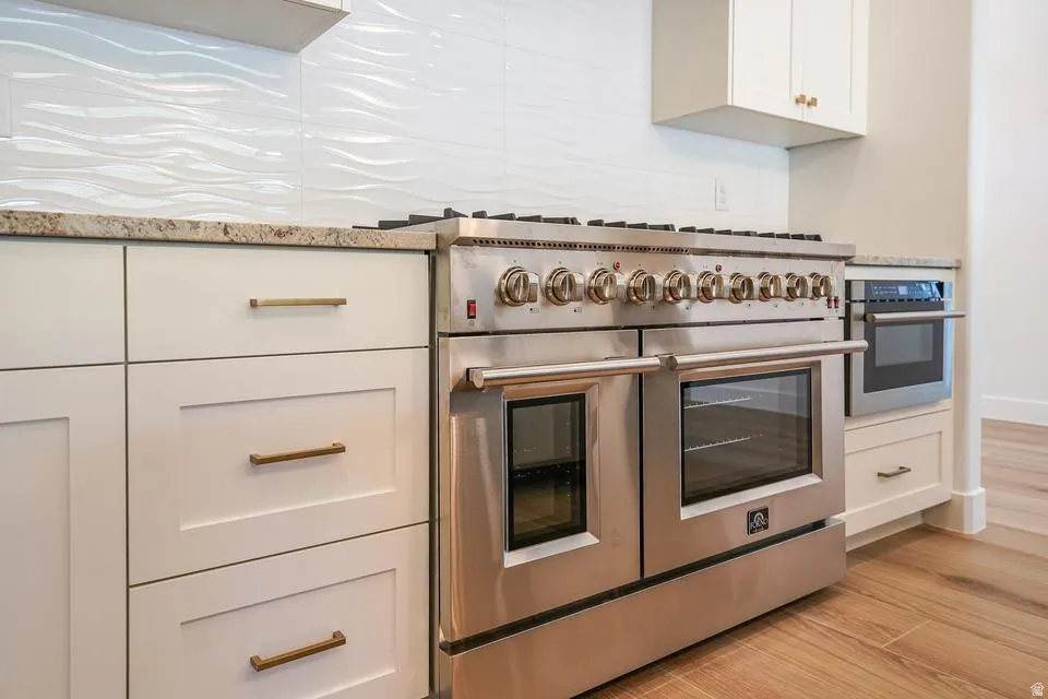Stainless steel professional-grade range with double ovens, complemented by a built-in microwave and light-toned cabinetry with brass hardware