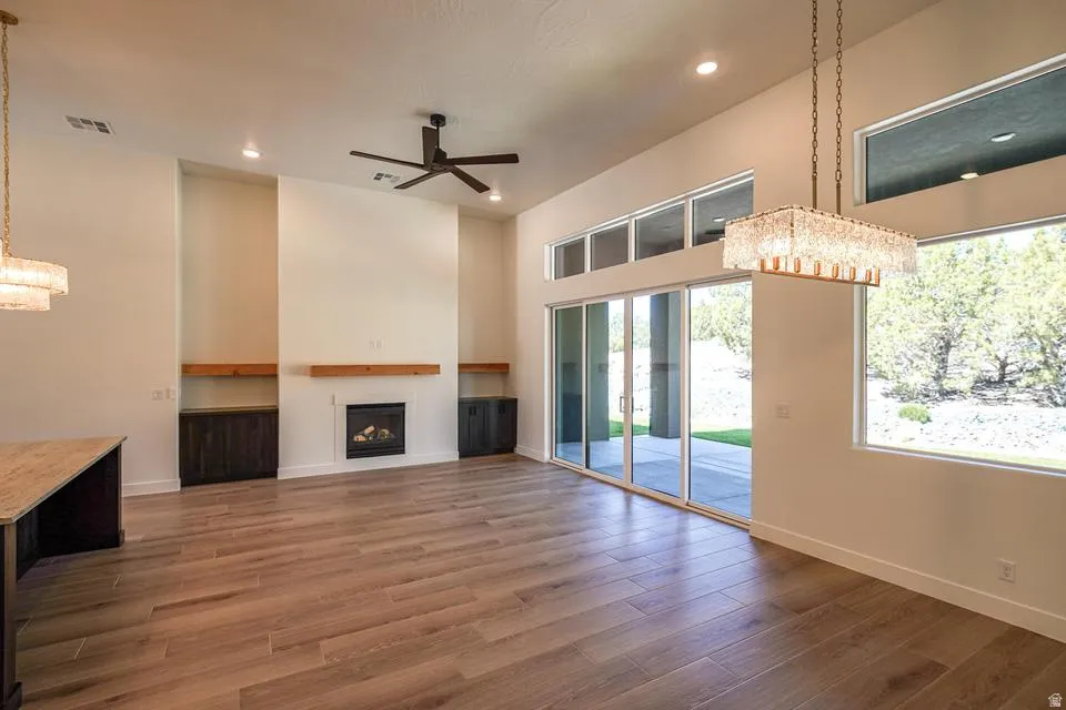 Spacious interior featuring wood-finish flooring, a contemporary fireplace with a wood mantle, built-in cabinetry, and a ceiling fan