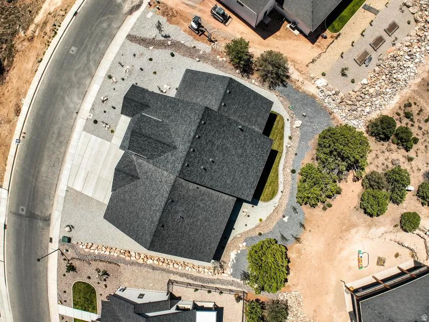 New construction residence featuring a dark shingle roof, extensive gravel landscaping, and a concrete driveway