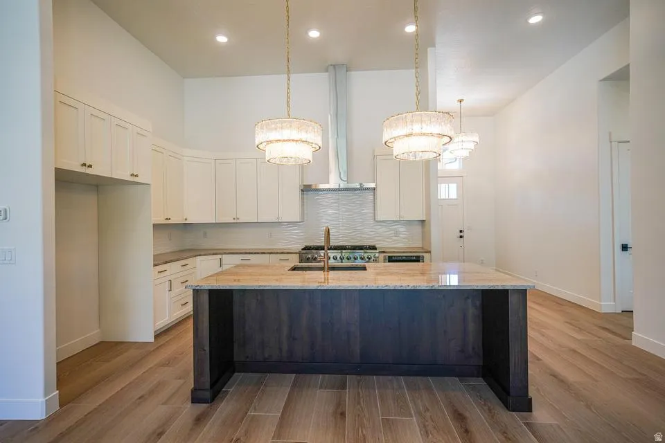 Kitchen featuring a large central island with a granite countertop, wood-finish base, and pendant lighting