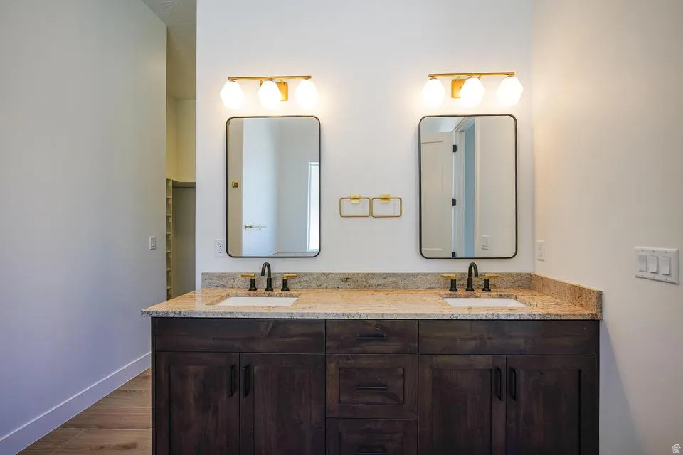 Double vanity featuring wood-finish cabinetry, light-toned countertop, and matte black fixtures