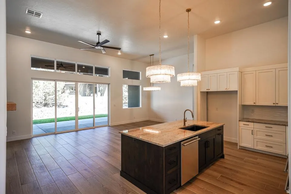 Spacious kitchen featuring a granite-topped island with an undermount sink and stainless steel dishwasher