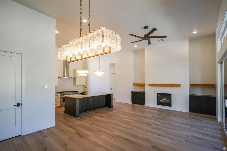 Spacious open-concept living area featuring wood-finish flooring, a contemporary fireplace with a wood mantle, and built-in cabinetry
