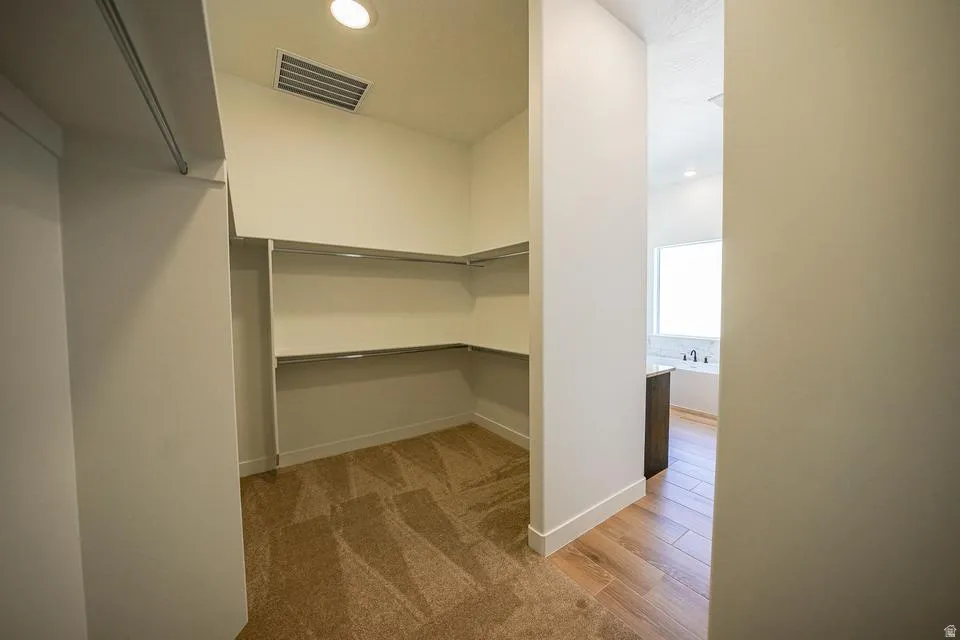 Spacious walk-in closet featuring carpet flooring, built-in shelving, and hanging rods