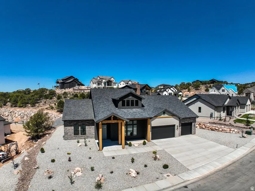 Modern ranch-style residence featuring a dark gray shingle roof, stone and siding exterior, and an attached two-car garage