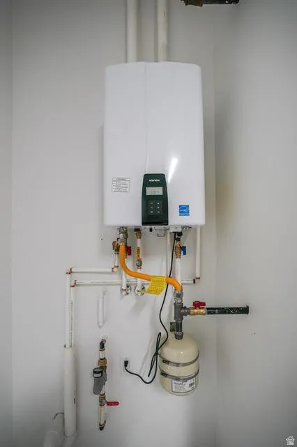 Wall-mounted tankless water heater with visible plumbing and expansion tank