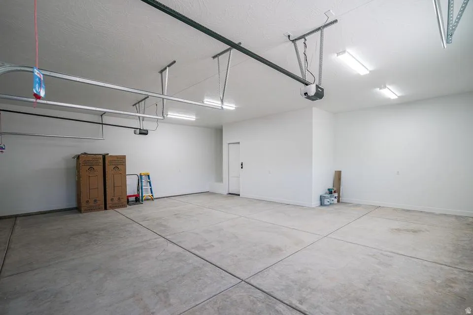 Spacious garage featuring a concrete floor, painted walls, overhead lighting, and an automatic garage door opener system