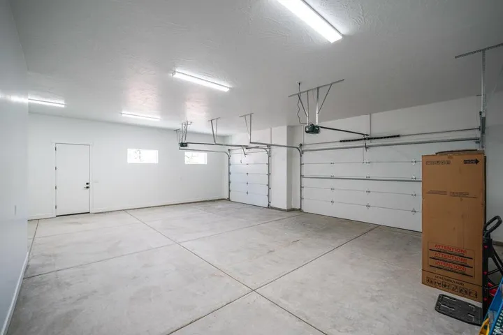 Spacious multi-car garage featuring a concrete floor, two overhead doors, and ceiling-mounted fluorescent lighting