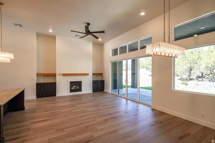 Spacious interior featuring wood-finish flooring, a contemporary fireplace with a wood mantle, built-in cabinetry, and a ceiling fan