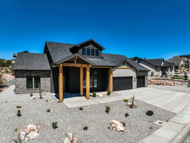 Contemporary residence featuring a dark facade with stone accents, a prominent wooden entry portico, and a two-car garage