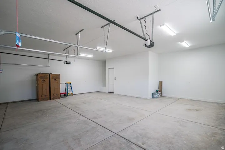 Spacious garage featuring a concrete floor, painted walls, overhead lighting, and an automatic garage door opener system