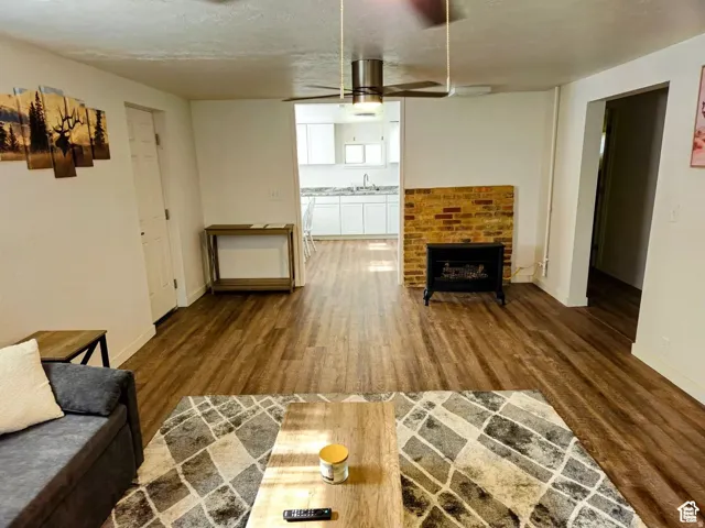 Unfurnished living room with a brick fireplace, dark wood finished floors, and a textured ceiling