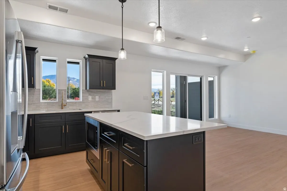 Kitchen with appliances with stainless steel finishes, decorative backsplash, pendant lighting, light wood-style floors, and recessed lighting