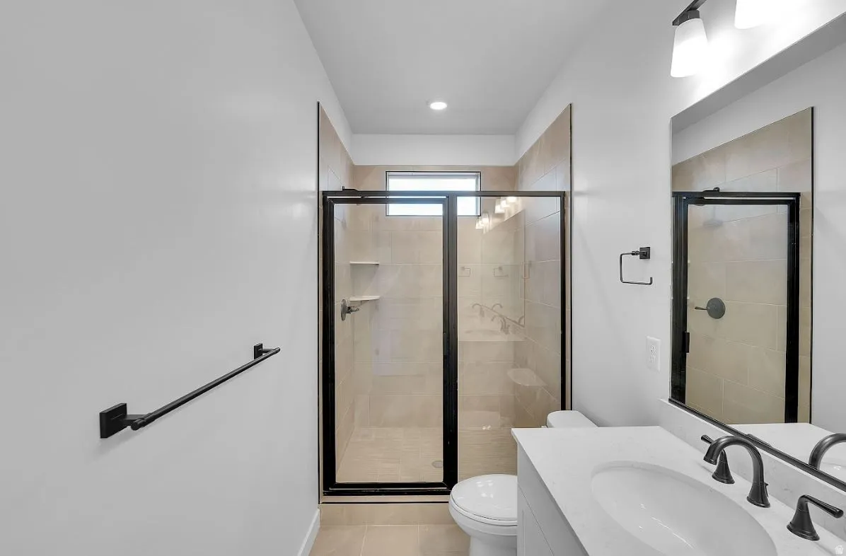 Full bathroom with vanity, a stall shower, and light tile patterned flooring