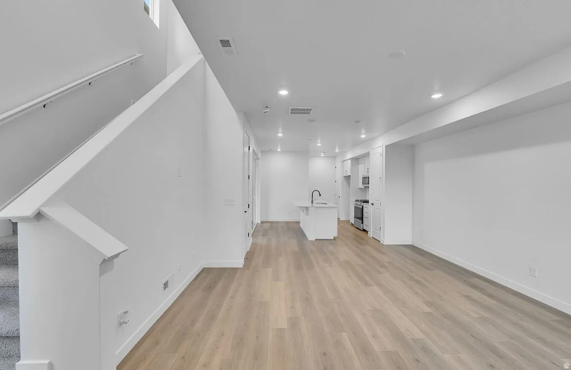 Unfurnished living room featuring stairs, recessed lighting, and light wood-style floors