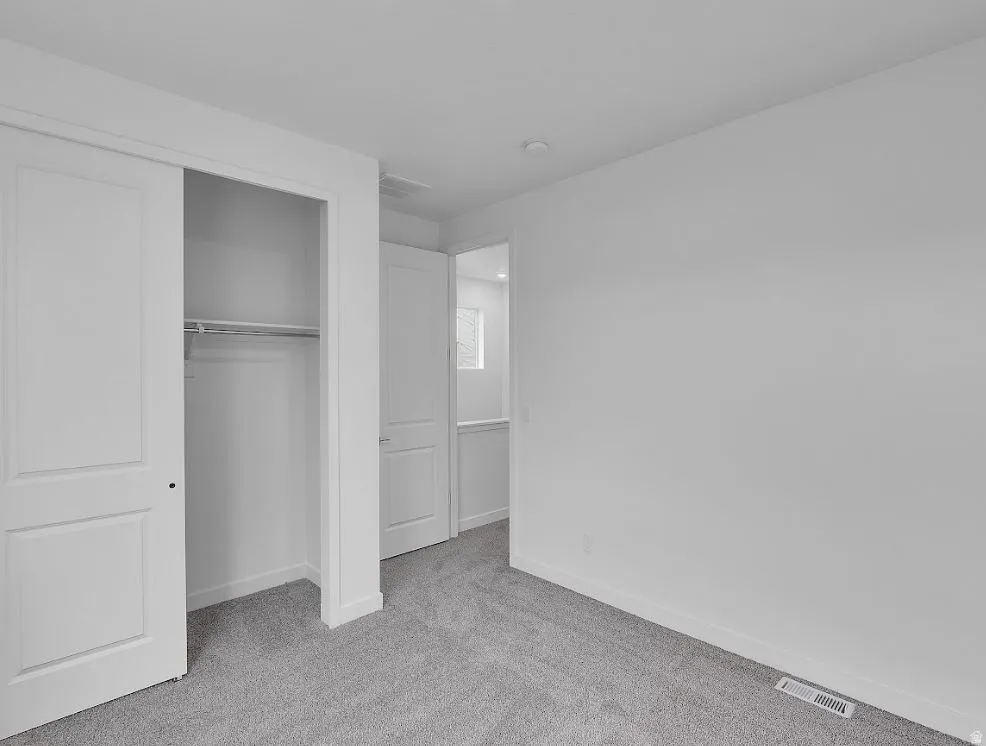 Unfurnished bedroom with light carpet and a closet