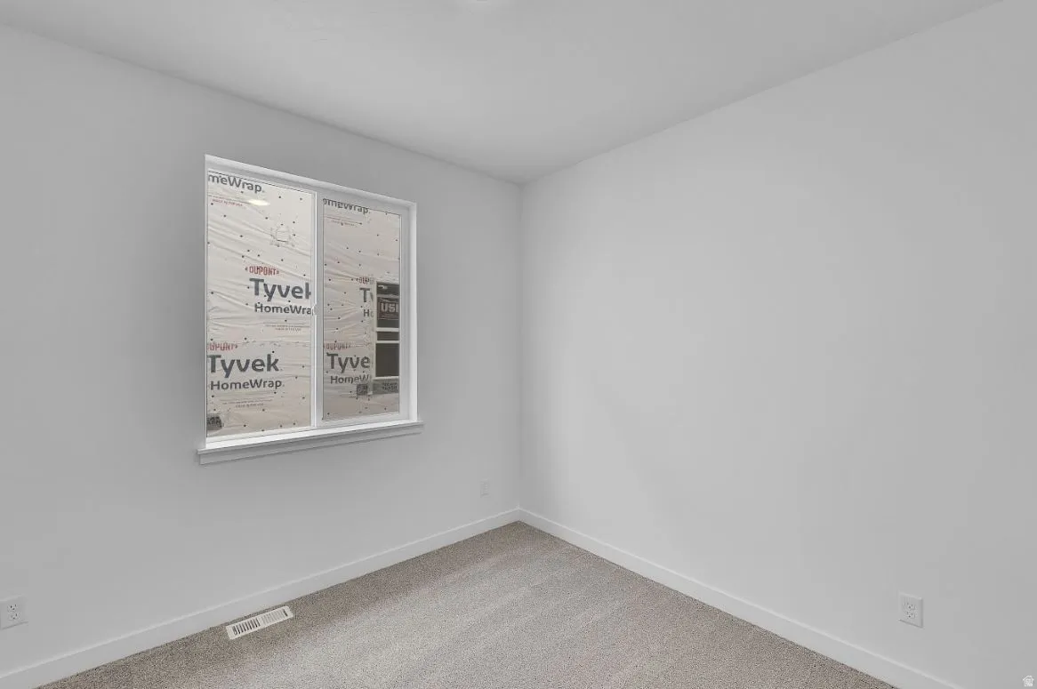 Empty room featuring carpet flooring and baseboards