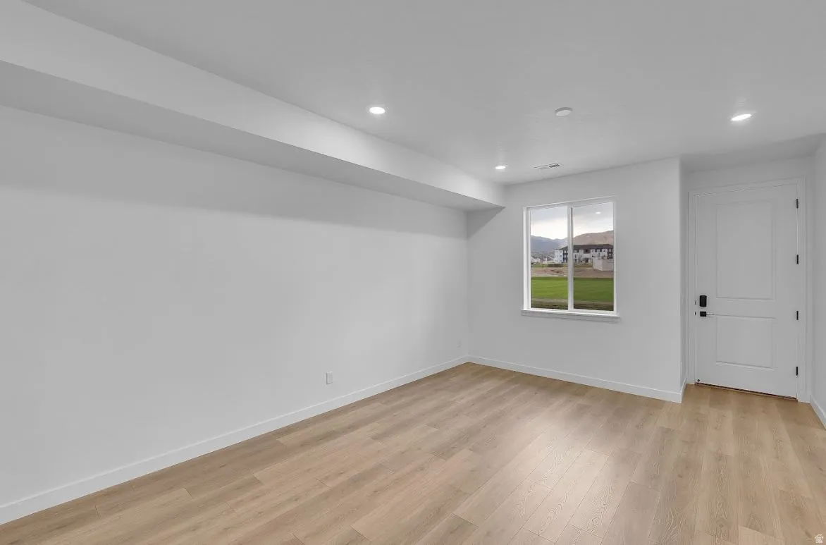 Empty room featuring light wood-type flooring and recessed lighting