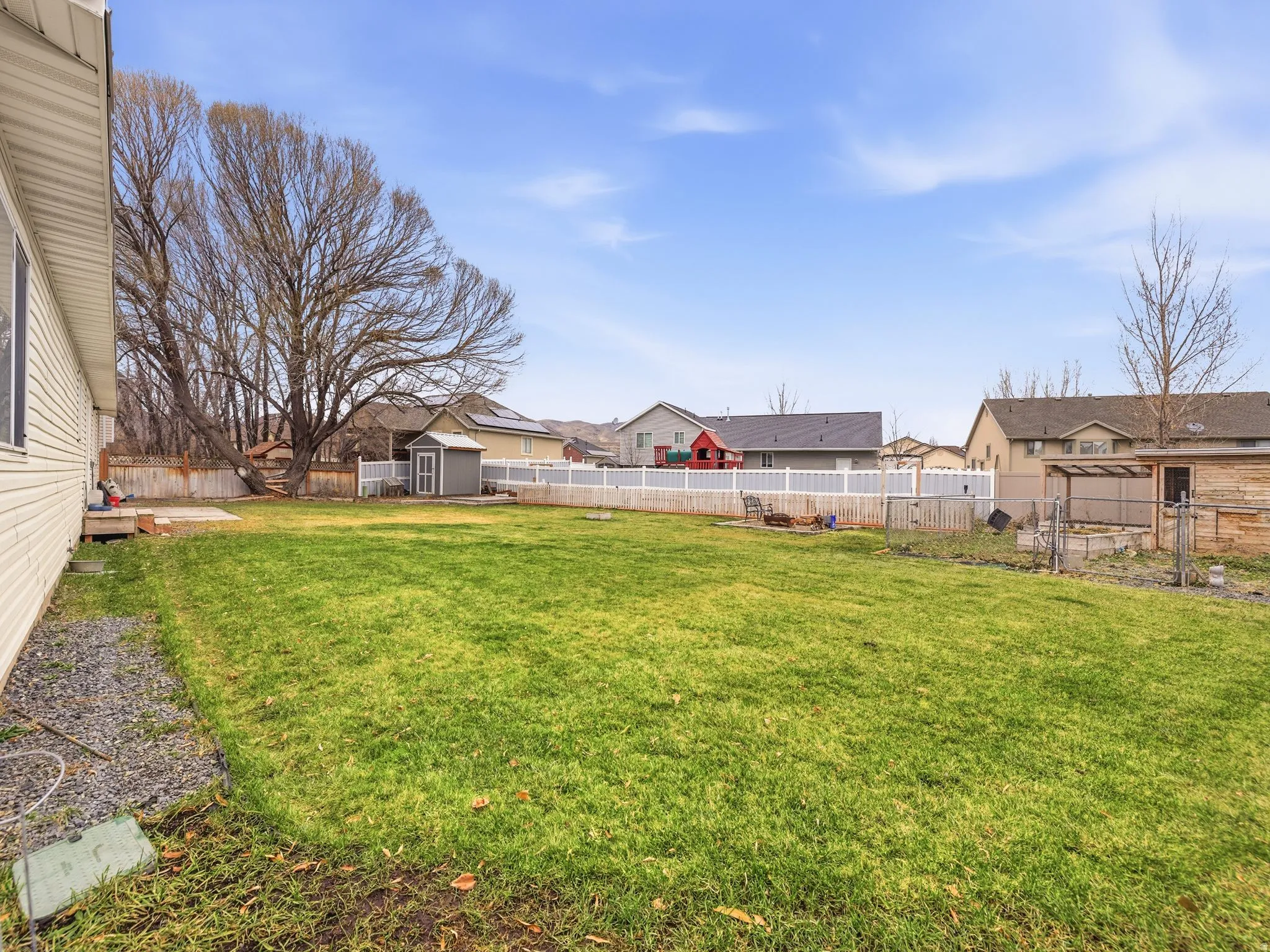 Fenced backyard featuring a residential view and a storage unit