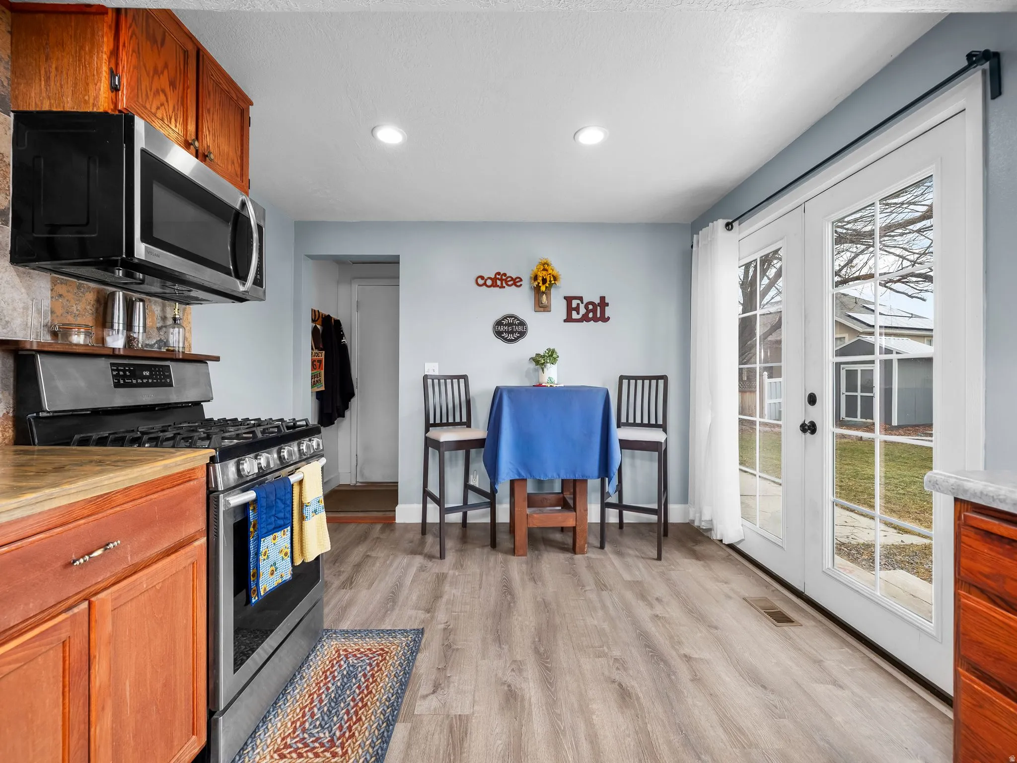 Kitchen with appliances with stainless steel finishes, brown cabinets, light wood-style flooring, recessed lighting, and french doors