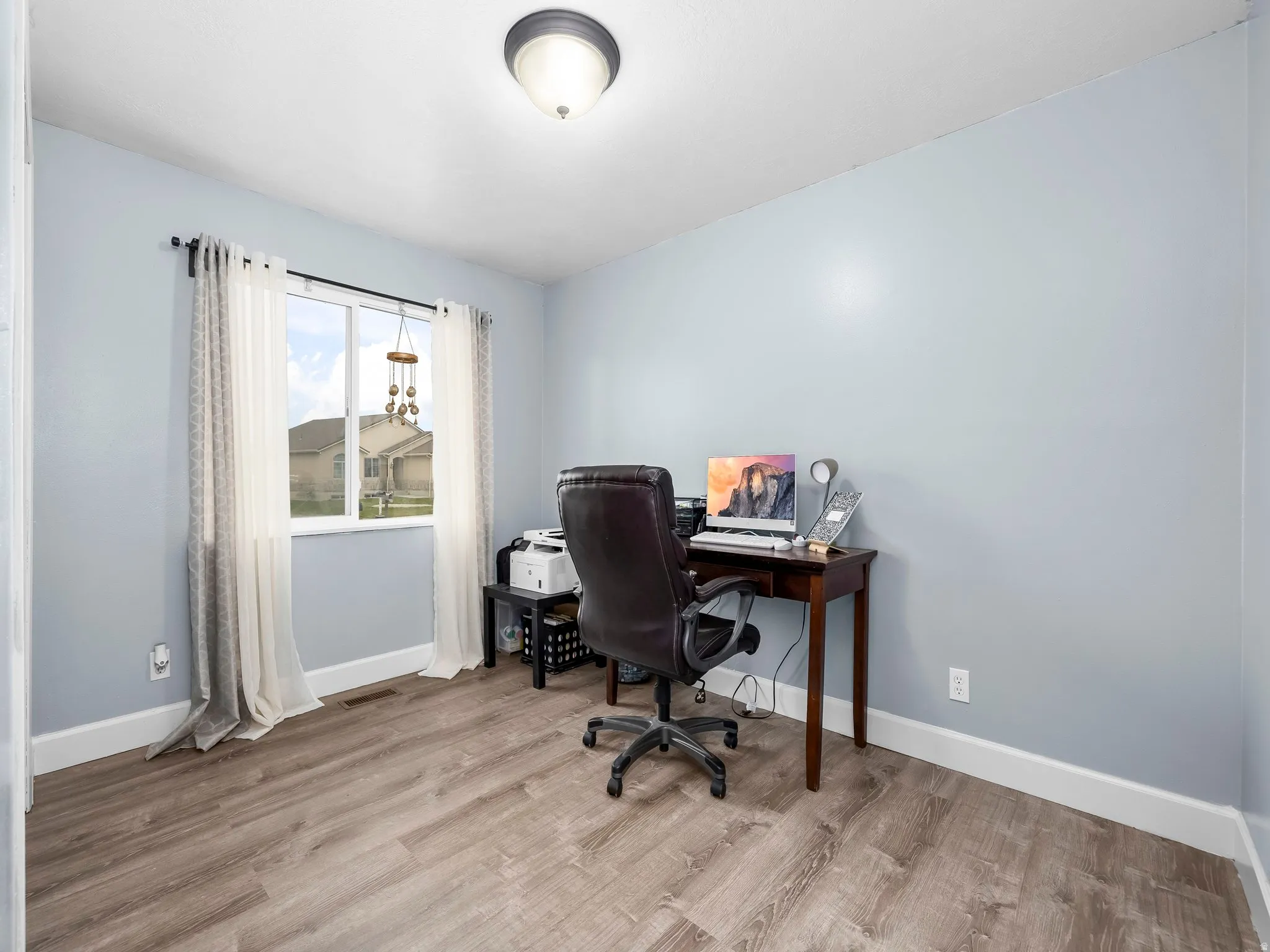 Home office with light wood-style flooring and baseboards