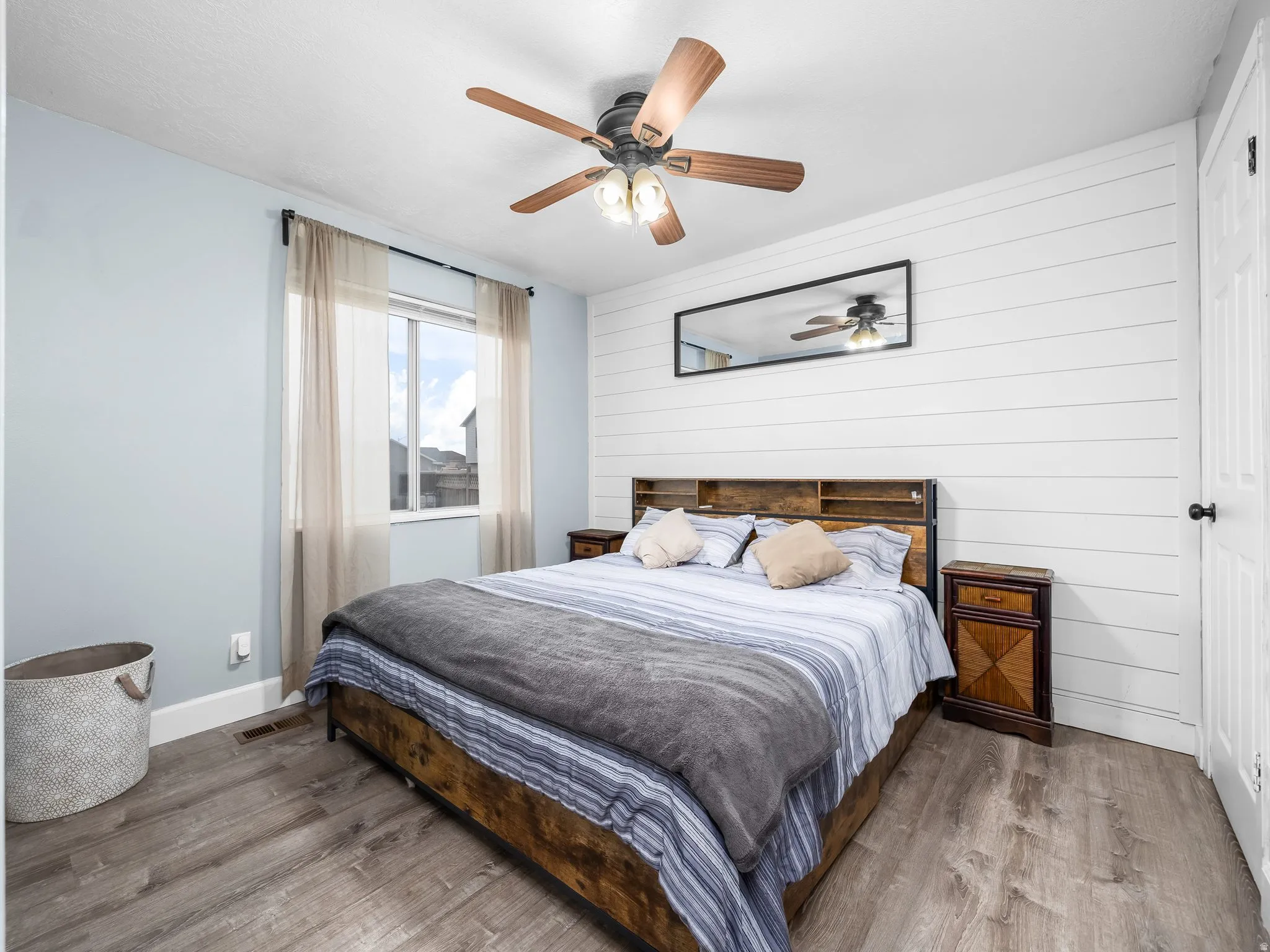 Bedroom with wood finished floors, a ceiling fan, and wooden walls
