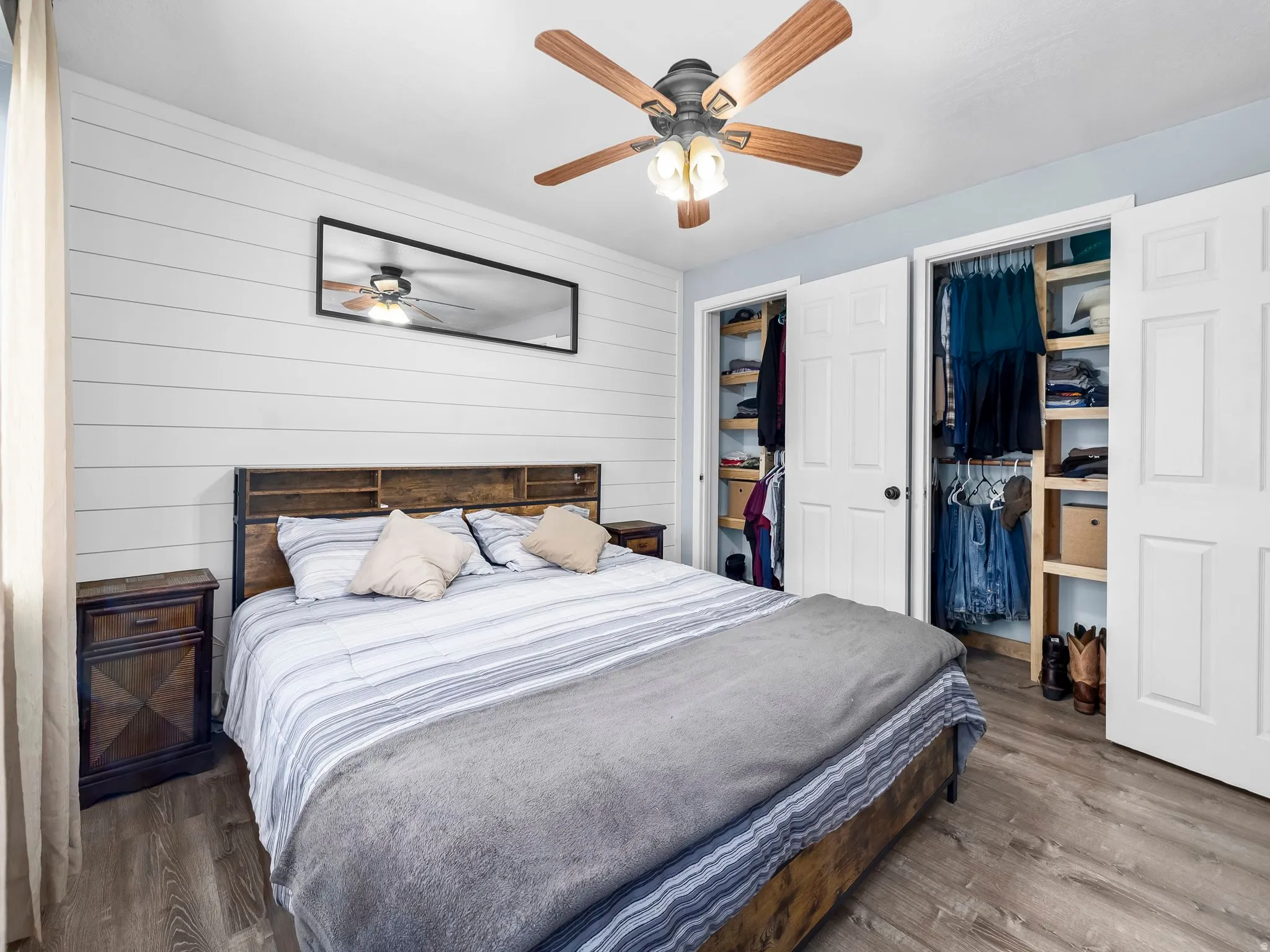 Bedroom featuring wooden walls, wood finished floors, and a ceiling fan