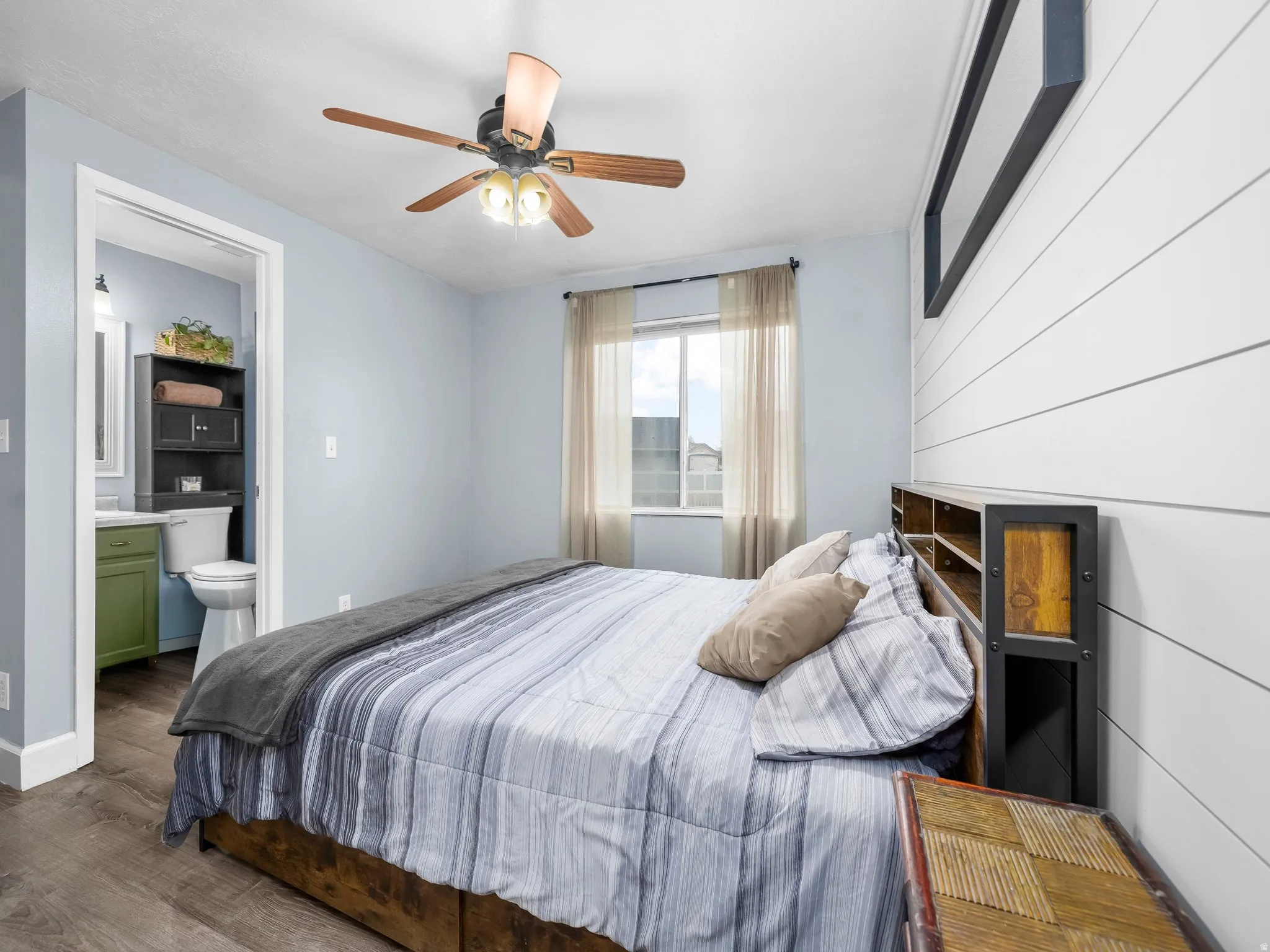 Bedroom with dark wood-type flooring, connected bathroom, and a ceiling fan