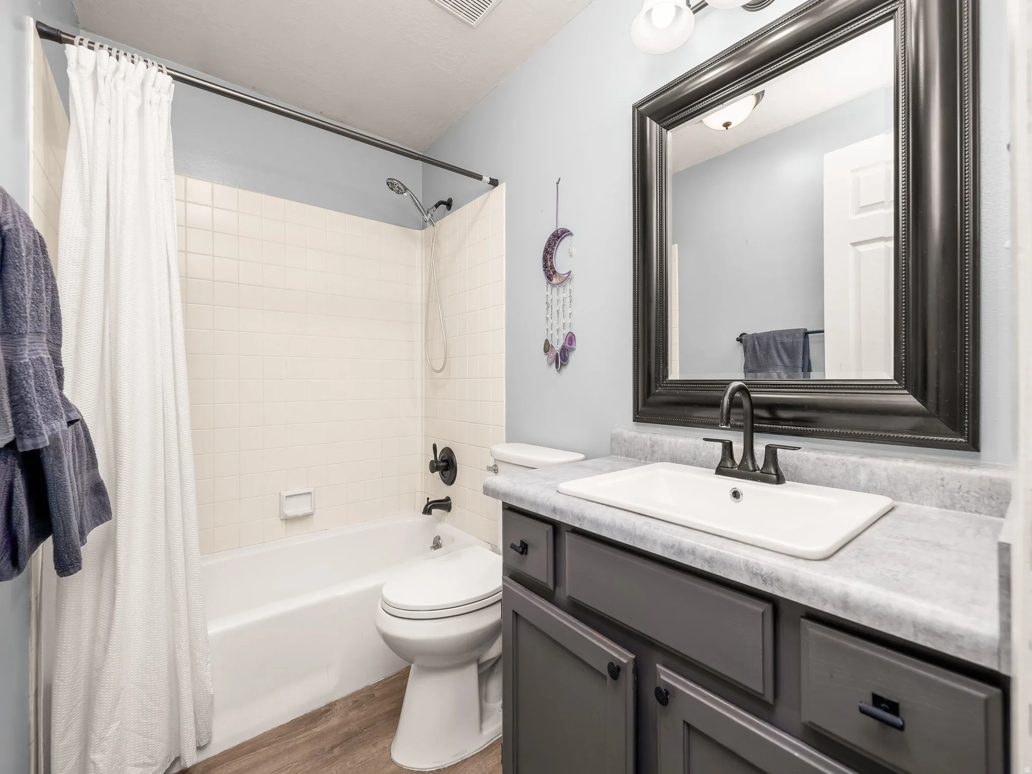 Bathroom featuring shower / tub combo, vanity, and light wood finished floors