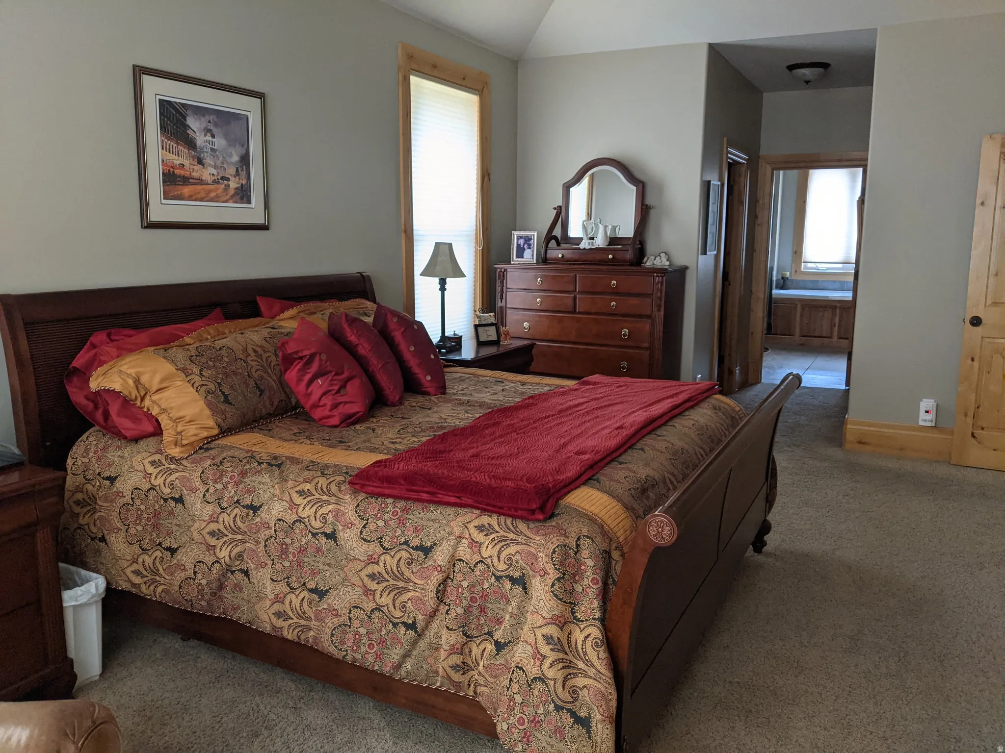 Bedroom featuring carpet floors, vaulted ceiling, and connected bathroom
