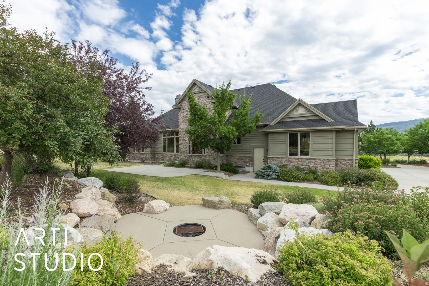 View of side of home featuring stone siding, an outdoor fire pit, roof with shingles, and a yard