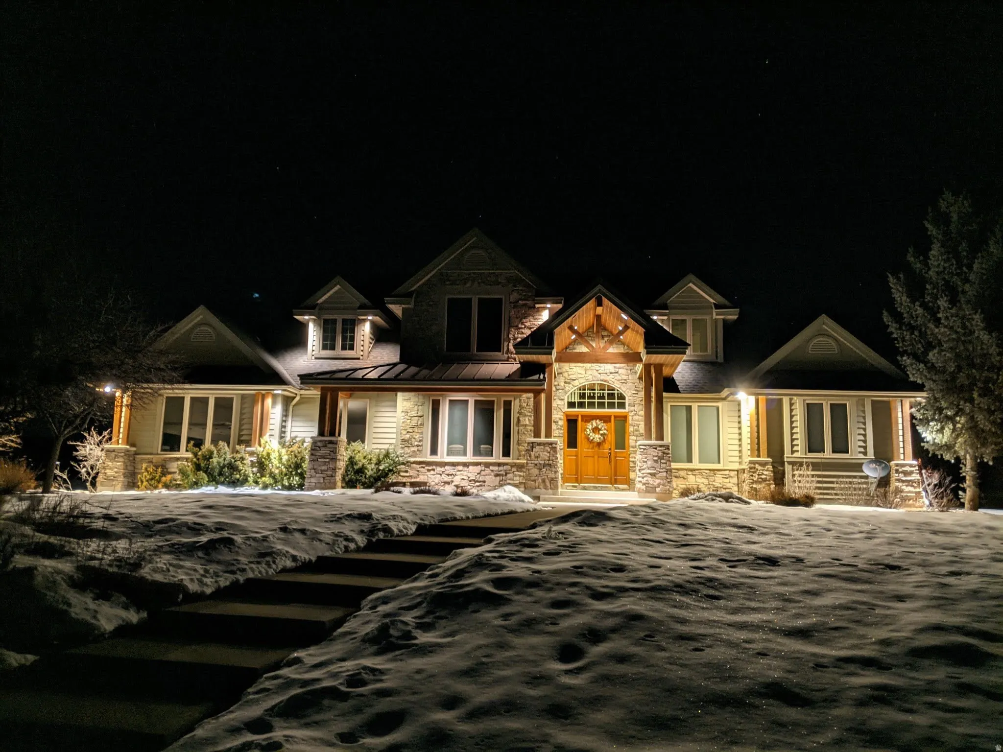 Craftsman-style home with stone siding, covered porch, a standing seam roof, and a metal roof