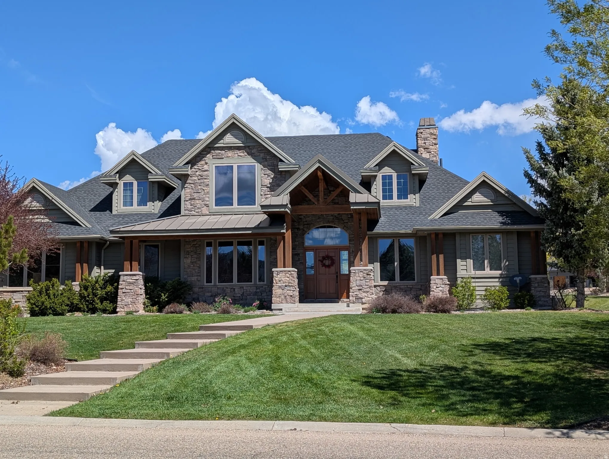 Craftsman inspired home featuring a front lawn, a shingled roof, a porch, stone siding, and a chimney