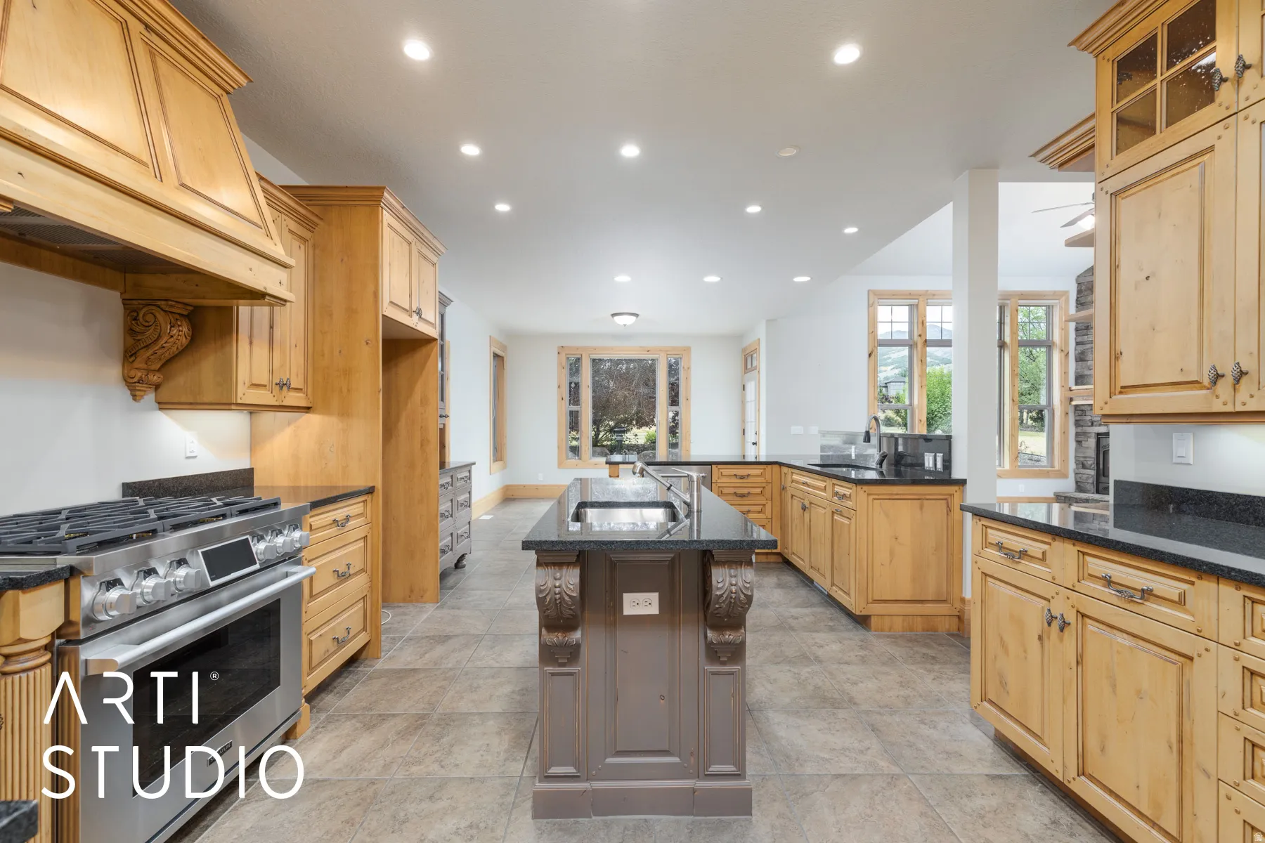 Kitchen featuring stainless steel gas range oven, dark stone countertops, an island with sink, custom exhaust hood, and recessed lighting